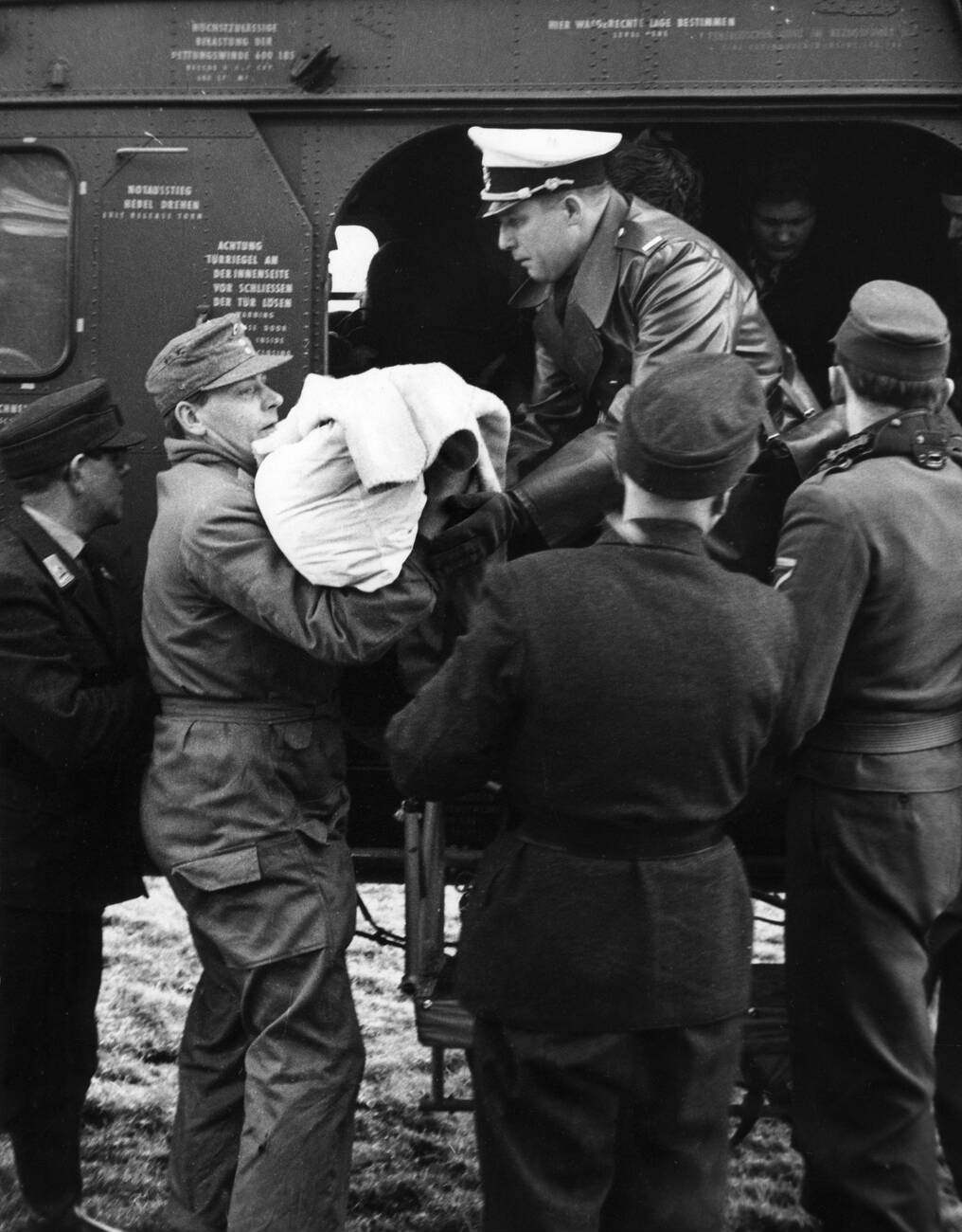 Unloading a helicopter during the North Sea flood of 1962 in Hamburg, West Germany with military, police, and Bundeswehr soldiers aiding in rescue operations