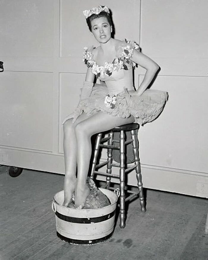 Cyd Charisse resting her feet on ice, behind the cameras after rehearsals in 1948