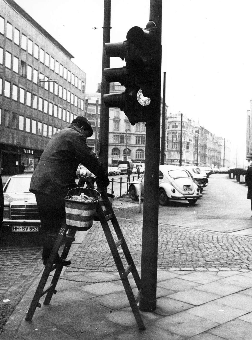 A man cleaning a traffic light in the Kaiser-Wilhelm-Strasse in Hamburg, Germany in 1970.