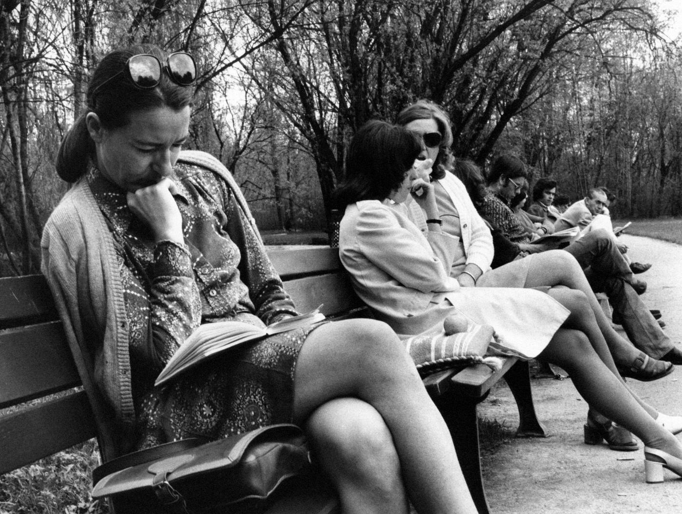 German woman reading a book on a bench in a park in Hamburg, Germany in 1973.
