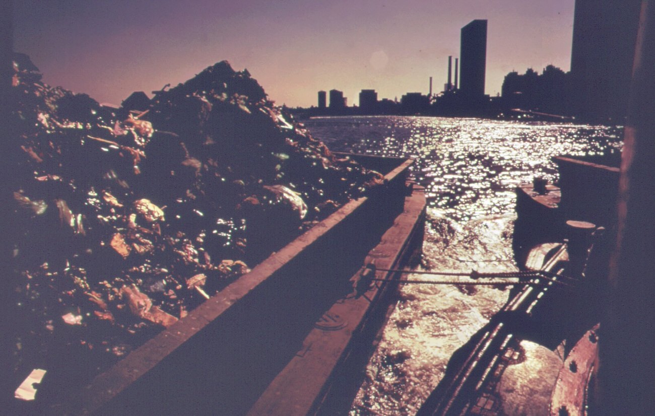 Part of the 26,000 tons of solid waste that new york city produces each day. Tugs tow heavily-laden barges down the east river to the overflowing staten island landfill, 1970s