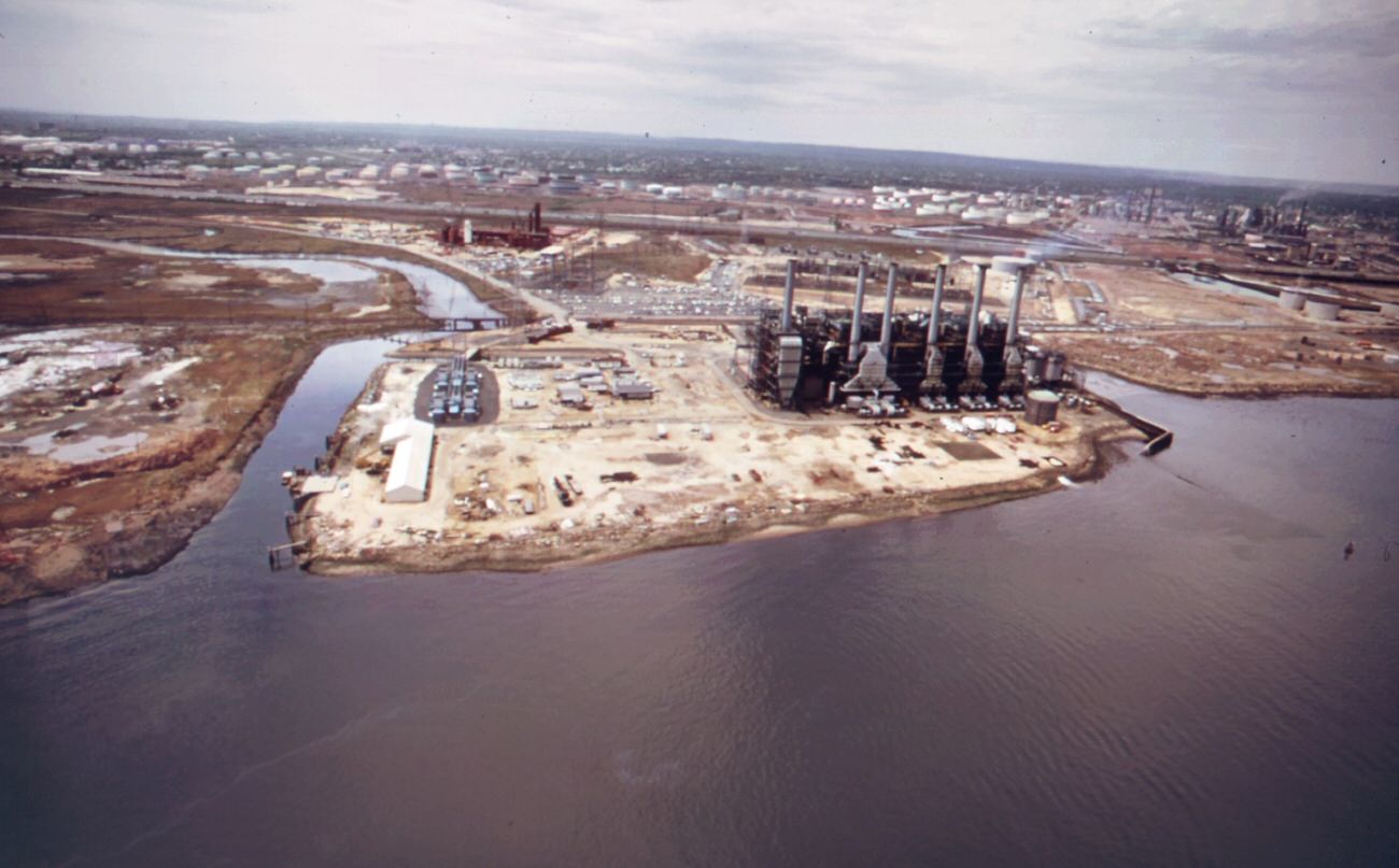 Industrial plant owned by agrico, overlooking the arthur kill, which flows between the new jersey shore and staten island behind the plant is the avenel housing community, and further back the colonial tank farm, 1970s