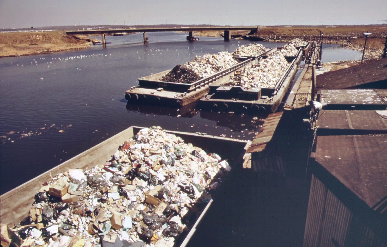 Garbage scows from manhattan wait to be unloaded at the staten island landfill, 1970s