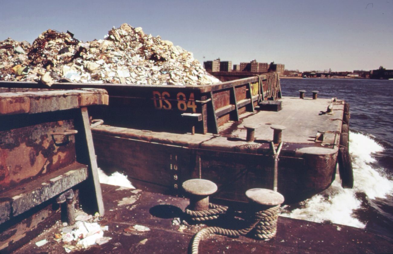 Garbage is towed down the east river to staten island landfill, manhattan in background, 1970s