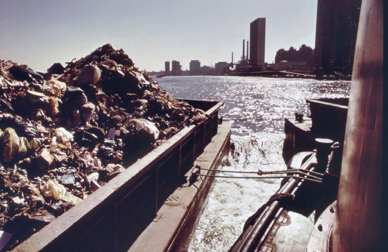 Garbage is towed down the east river to staten island landfill, manhattan in background, 1970s