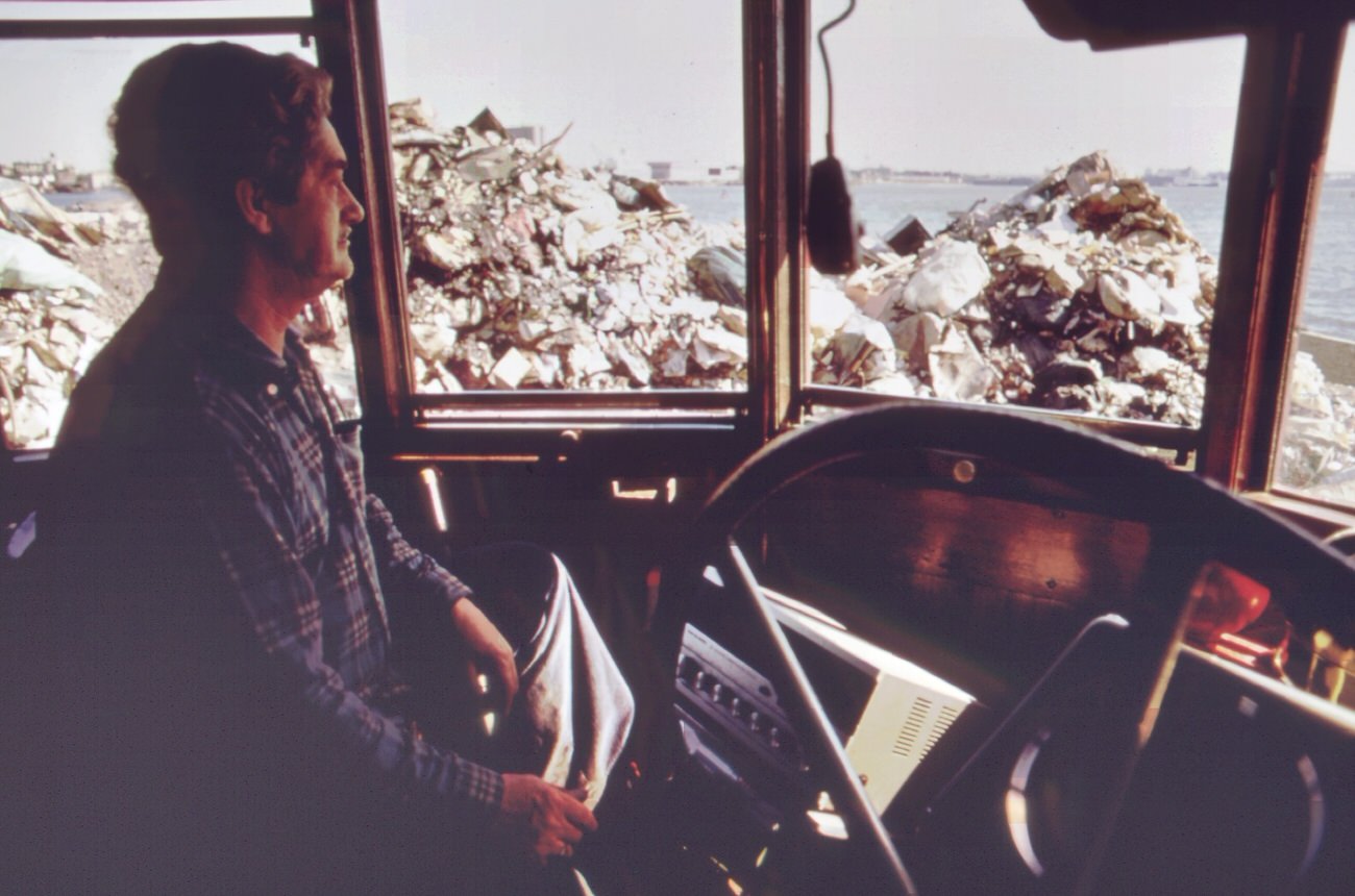 Operator of steam-shovel used to unload garbage scows from manhattan sits in his cab at staten island landfill, 1970s