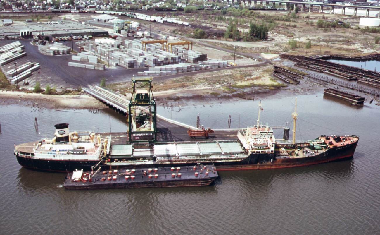 Chemical and containerized shipping of the union carbide company in the arthur kill. In the background is the outerbridge crossing to staten island, 1970s