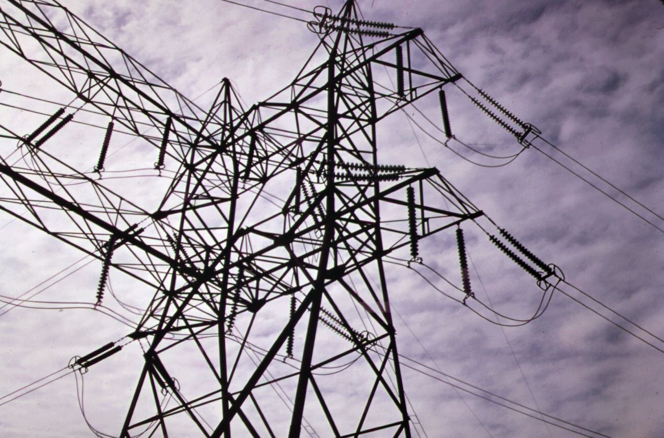 Transmission lines of electrical power station built on staten island marshland. Opening of verrazano bridge brought huge increase in construction to area, 1970s