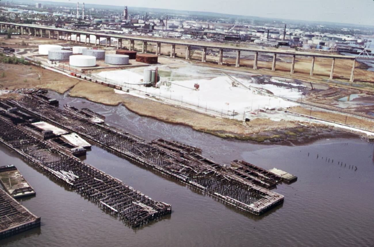 Petroleum shipping terminal at perth amboy on the arthur kill, showing oil slick from spill. In the background is the outerbridge crossing to staten island, 1970s