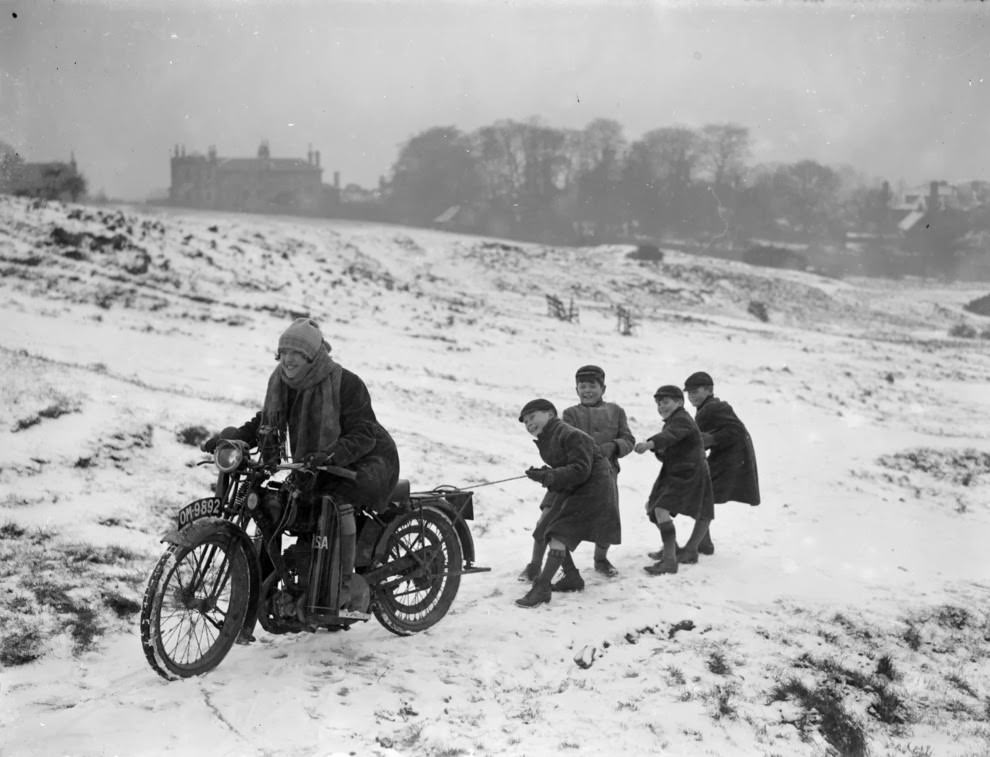 Children being pulled along by a woman on a motorbike in london, 1926.