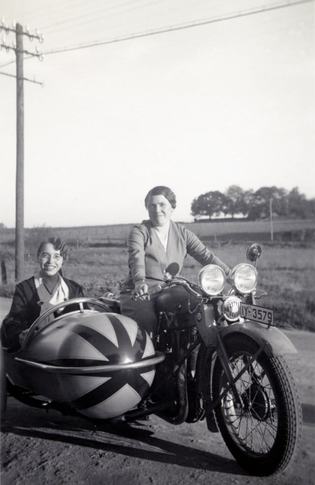 Two cheerful ladies posing with a opel motoclub 500 combination on a dirt road in the countryside. The bike is registered in the administrative region of düsseldorf, circa 1930s.