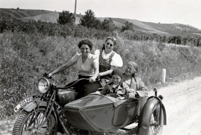 Three generations of an austrian middle-class family posing with a indian chief combination on a gravel road in summertime. The sidecar motorcycle is registered in the city of vienna, circa 1939.