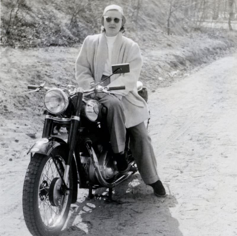 An elegant lady posing in the saddle of an nsu konsul in the countryside, circa 1950s.