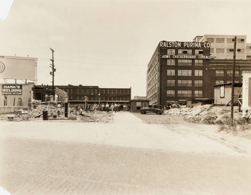 Workers clearing debris from a partially collapsed building near 835 S. 8th Street. Buildings for the Ralston Purina Co., 8th Street Scale, and Hank's Welding can be seen, 1930