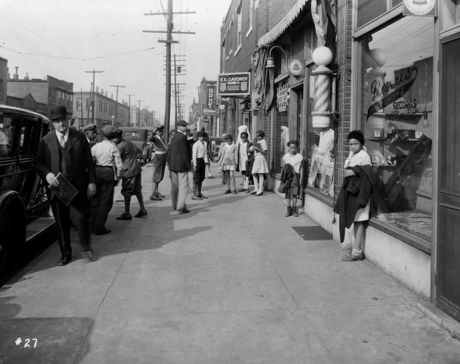 Street view of Louis Lum Chop Suey at 1014 North Sarah and other businesses. Several people are on the busy sidewalk, 1930