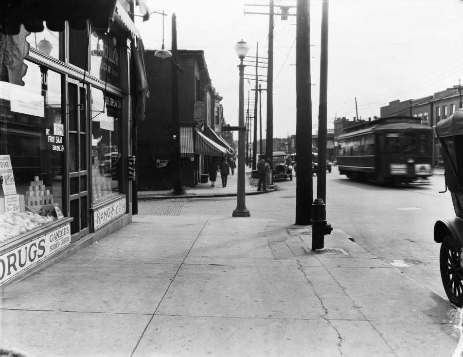View looking east from Goedde-Igel Drug Co. at 5801 Easton with bustling foot traffic, cars, and streetcars, 1930