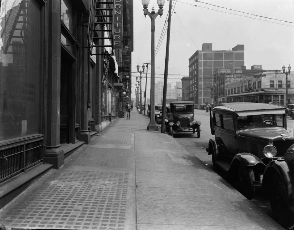 View looking east down Olive from west of 18th Street. Several businesses including Quirk Luggage, Paris Hotel, Draper Drug Company, and Walker-Armstrong House Furnishing Company are visible, 1930