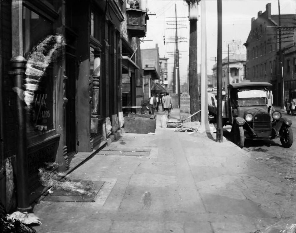 View of storefronts on the 800 block of North Jefferson between Morgan and Franklin. Sign for Joseph Berzon's tailor shop and other businesses are visible, 1930