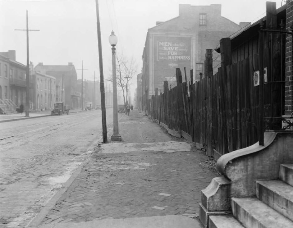 View of North Tenth St. near O'Fallon St., including a junkyard, with a building painted with the message "Men who fail to save surely must forfeit future happiness", 1930