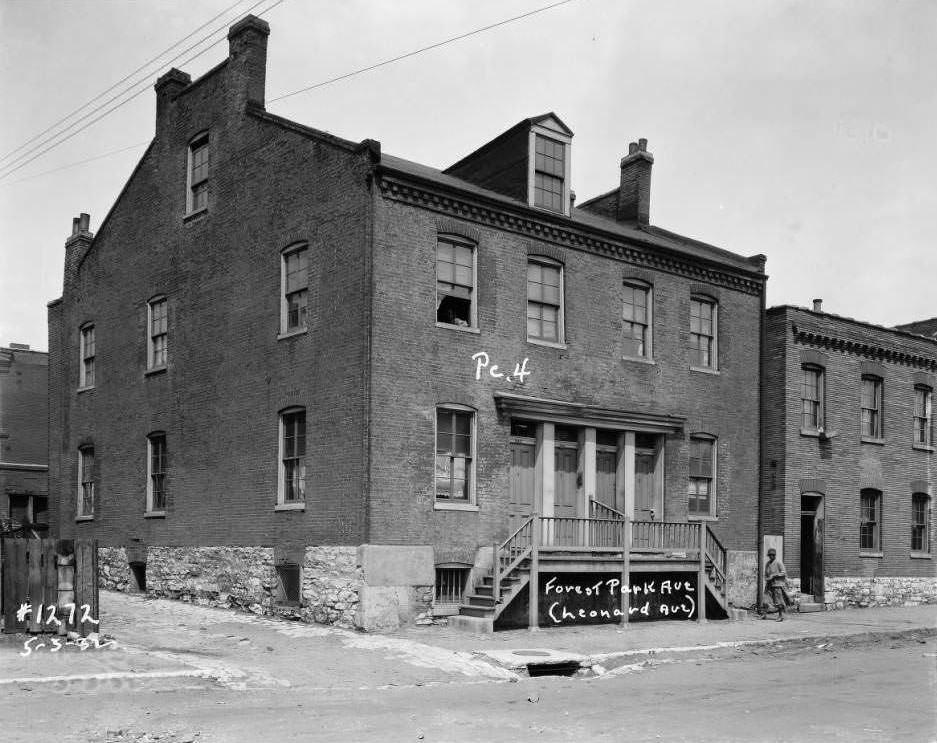 View of multi-family brick dwelling on Forest Park Ave. with a woman on the sidewalk, 1932.