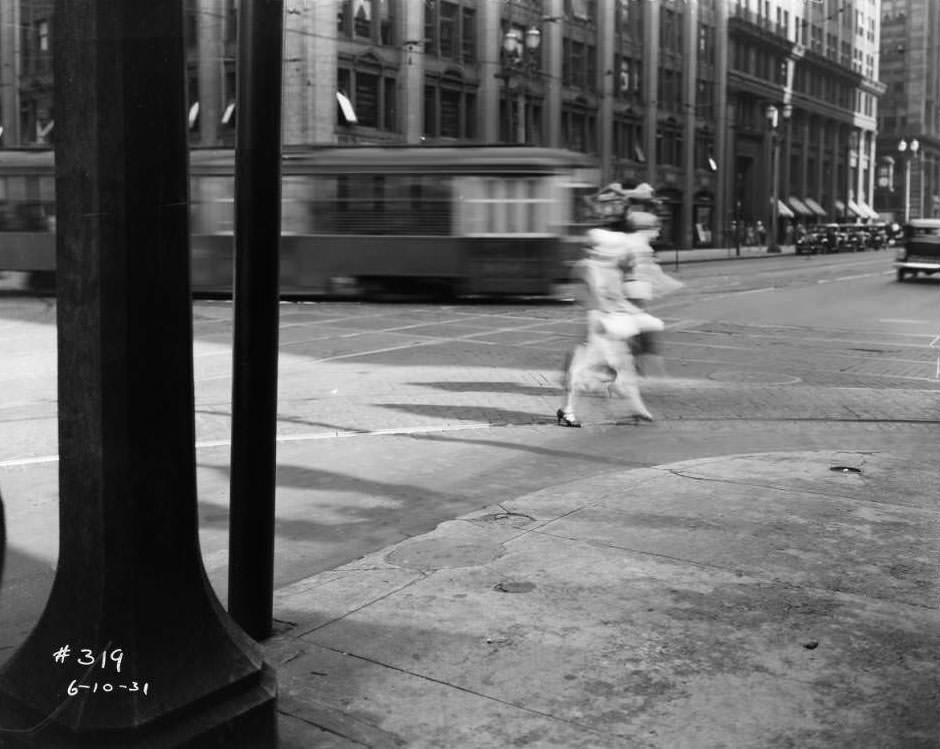 Two women crossing Broadway at Locust as a streetcar passes behind them, 1931