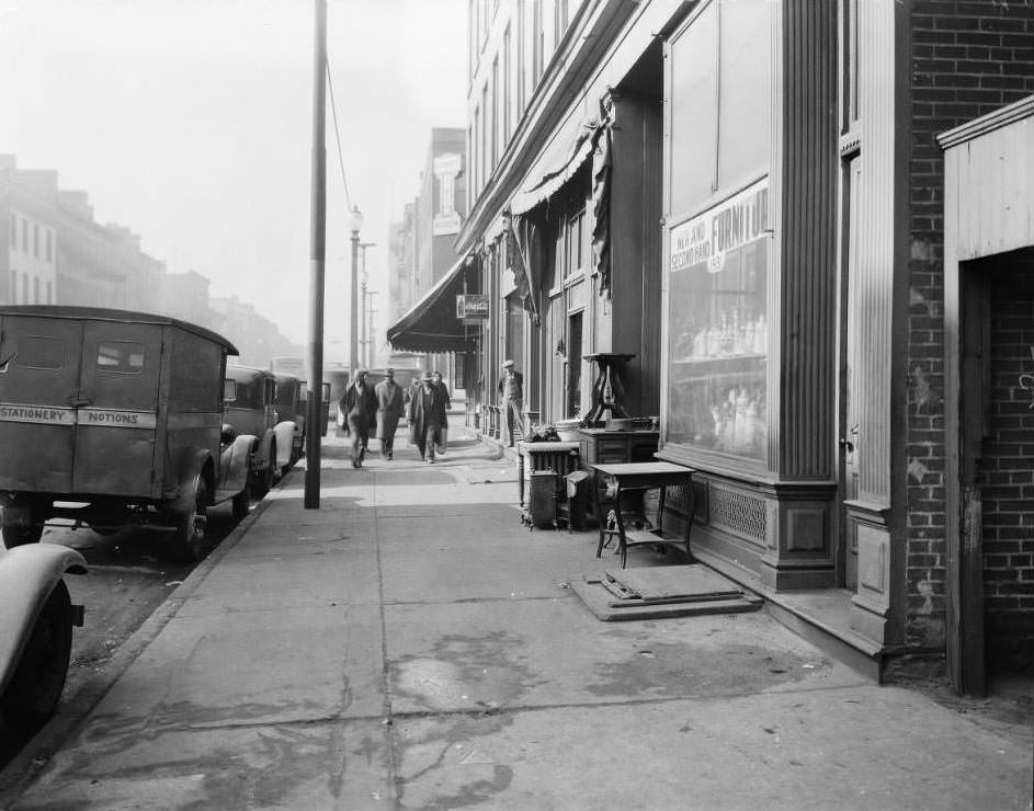 Pedestrians and parked cars near Ludwig's Drugs at 1939 Franklin Avenue with a used furniture store in the foreground, 1930