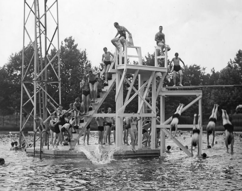 Boys and girls of all ages swarm over the diving tower at the Marquette Pool as it opens for the season, 1930