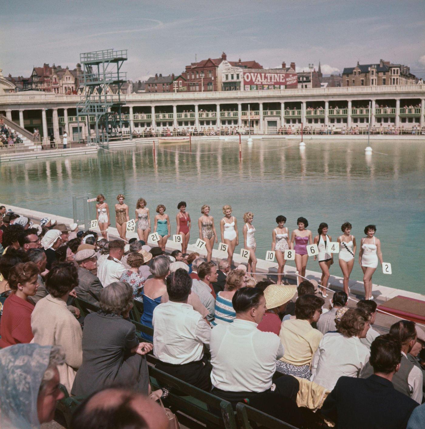 A line up of women pose in bathing suits as they take part in a beauty contest at South Shore open air swimming pool, 1960
