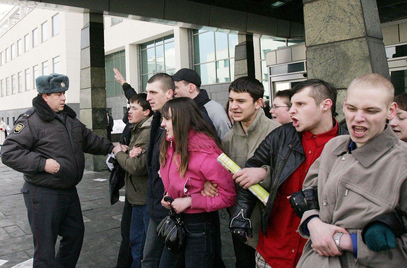 Russian policeman detains National-Bolshevik Party members during protest outside "Sberbank" in Moscow demanding compensation for savings lost during Soviet collapse in 1991.