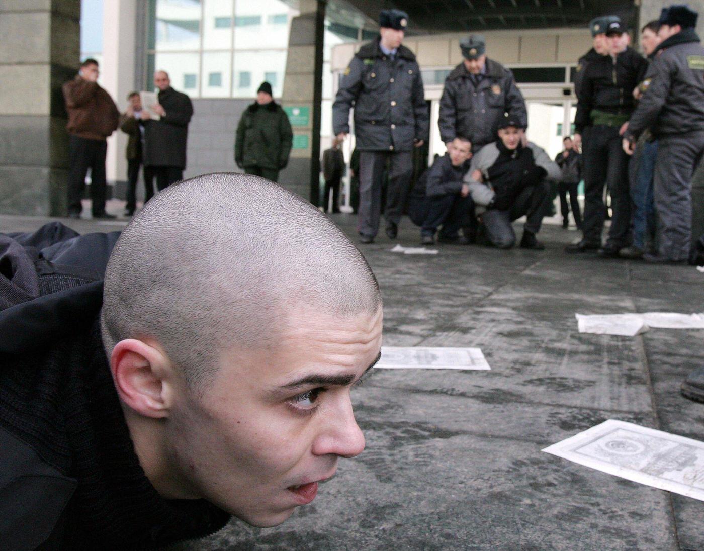 National-Bolshevik Party member lies on ground after being arrested by Russian police during protest outside "Sberbank" in Moscow demanding compensation for savings lost during Soviet collapse in 1991.
