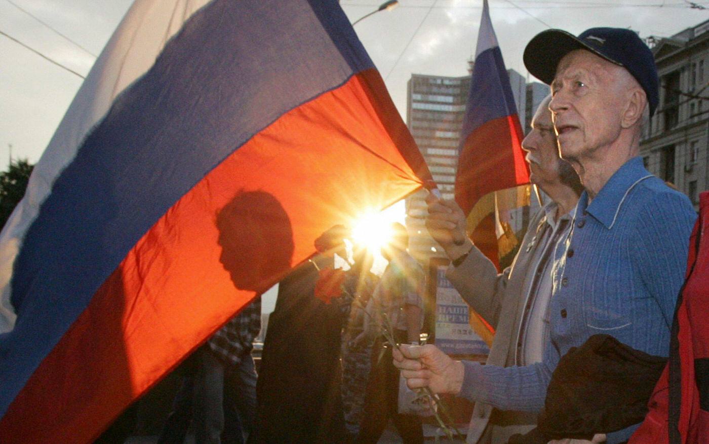 Man carries Russian flag during rally in Moscow commemorating the 15th anniversary of the failed 1991 coup that led to the re-birth of independent Russia.