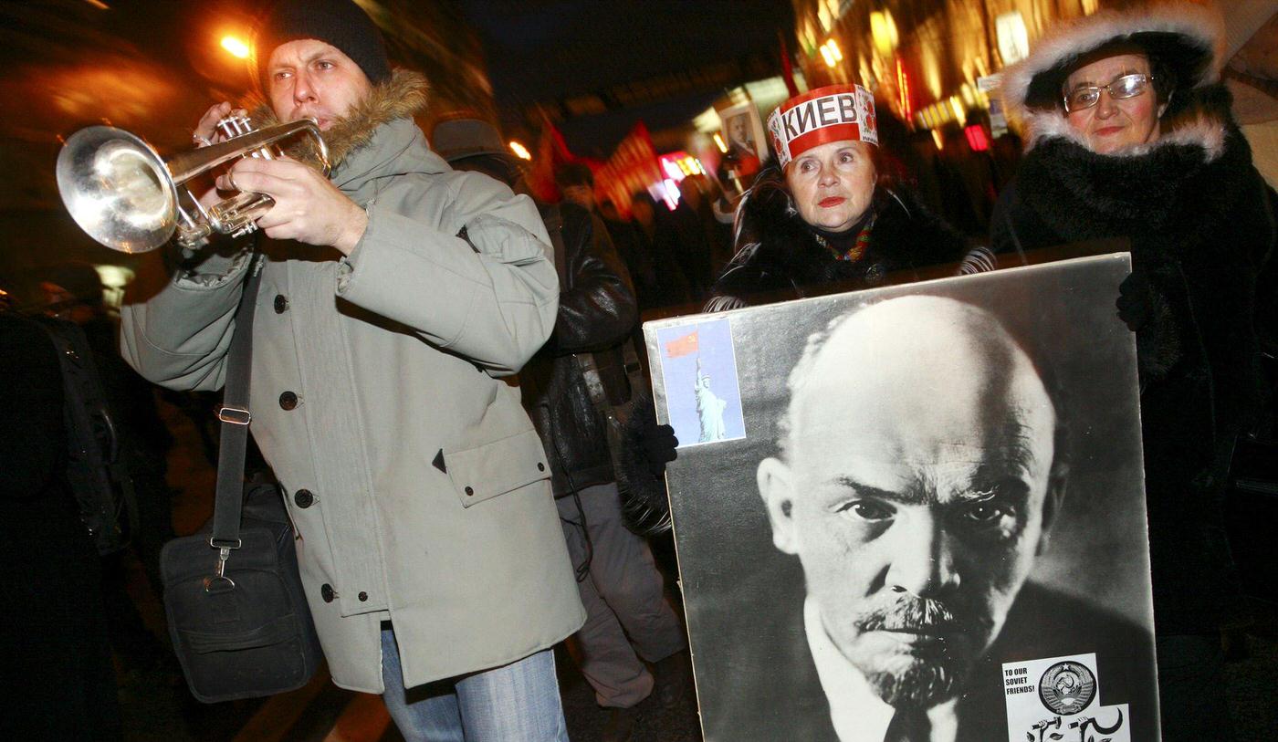 Russian Communist supporter carries Lenin picture as man blows trumpet during rally in central Moscow marking 90th anniversary of Communist overthrow of the tsarist empire.