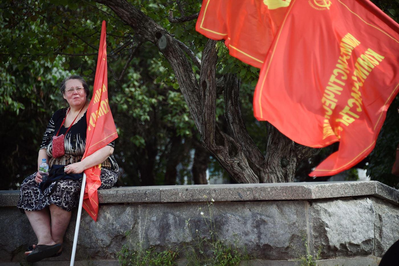 Russian Communist supporter with red flag sits on a wall during rally in downtown Moscow marking the 25th anniversary of the August 1991 putsch.