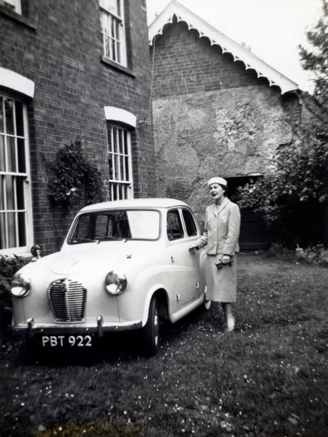 Elegant lady posing with an Austin A30 on the lawn of a back garden, 1955.