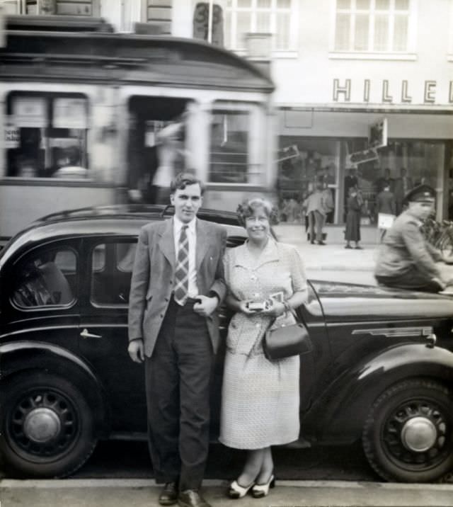 English couple posing with an Austin Eight, 1950.