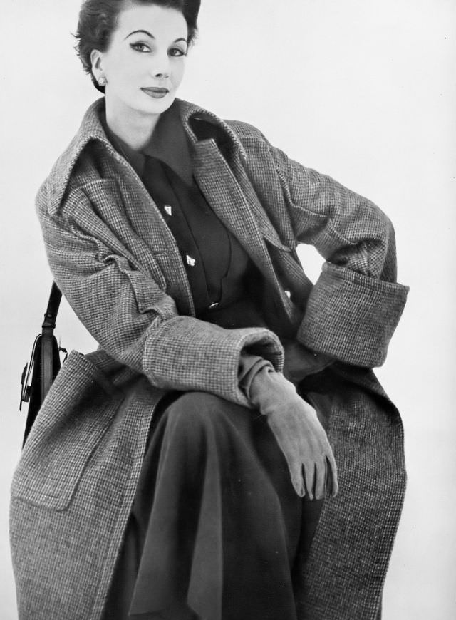 Barbara Goalen in a greatcoat in a porridgy tweed, welted and cuffed, with gold buttons by Matita, handbag by Finnigan, 1952.