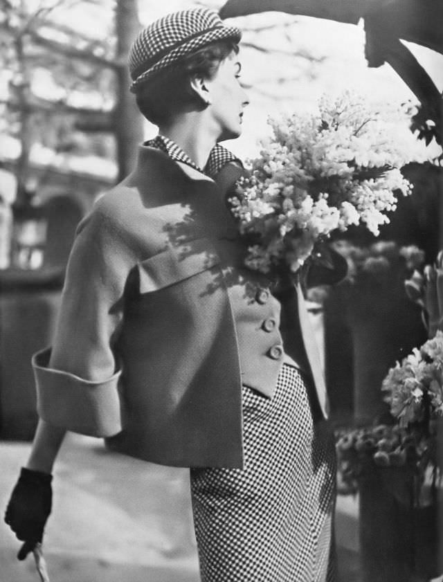 Barbara Goalen in black and white check shirtdress under an orange jacket fitted like a waistcoat in front and swinging loose behind by Robert Piguet, 1950.