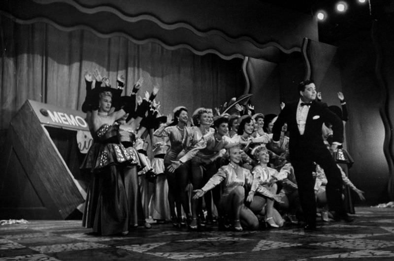Entertainer Jackie Gleason (C) executing his famous How Aweet It Is dance wlhile the chorus girls are taking a bow behind him, 1953.