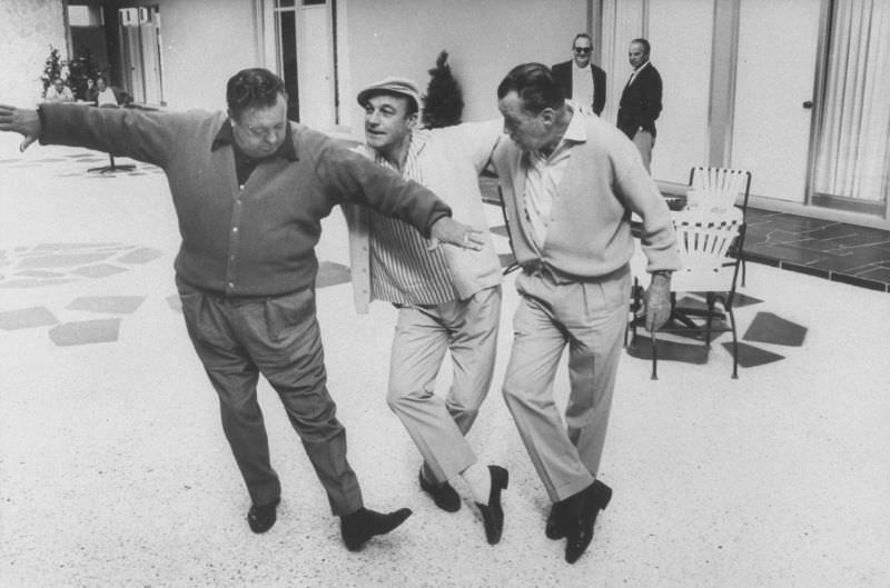 Actors Jackie Gleason and Gene Kelly casually tap dancing Ed Sullivan during visit to Gleason’s studio, 1967.