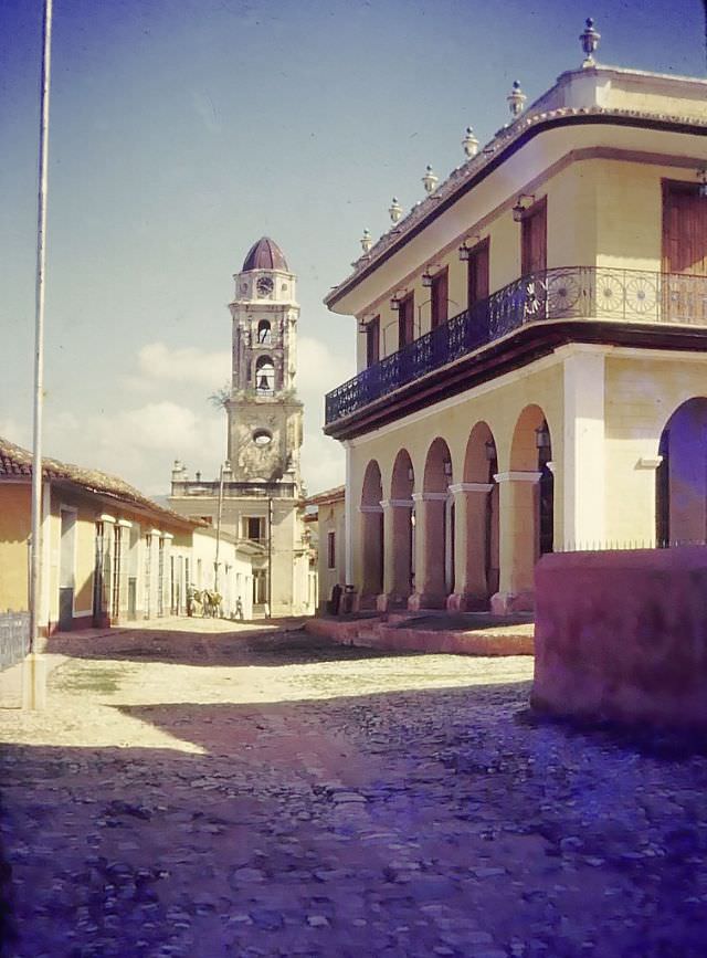 Clock tower with bell on a cobblestone street, 1950