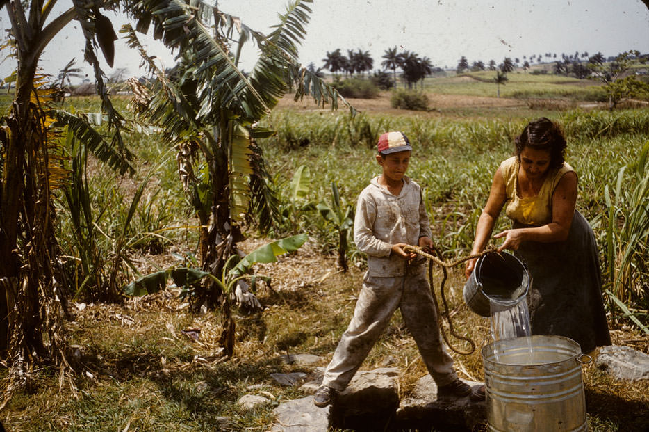 Boy and woman drawing water from well