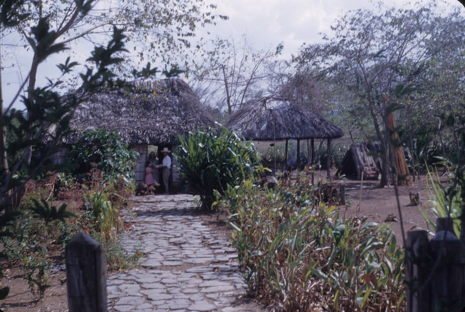 Couple and child in front of thatched building