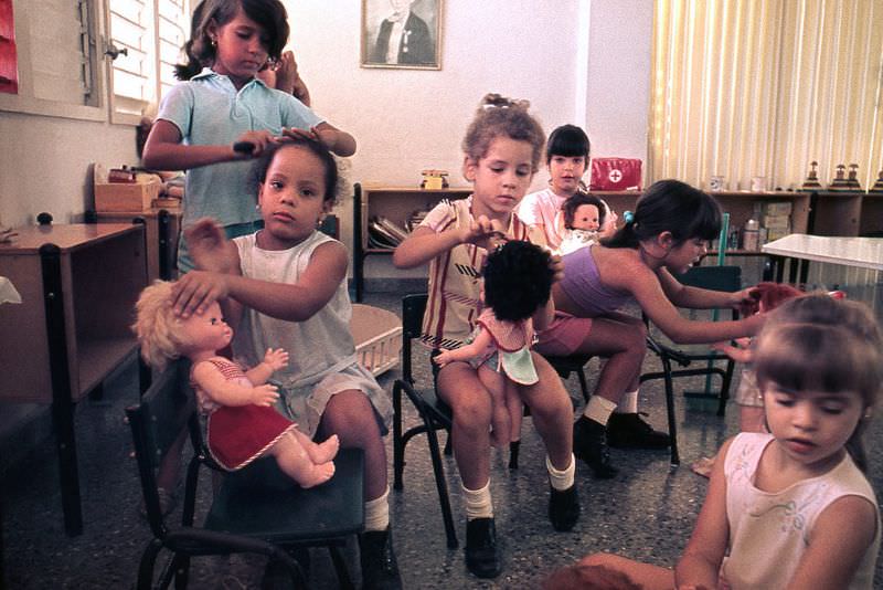 Girls playing combing dolls during recess at a nursery, Cuba, 1976