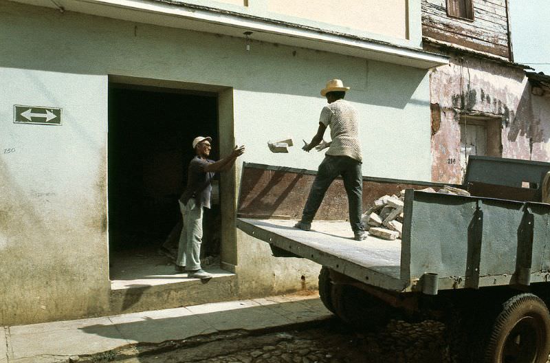 Two men unload a truck in the traditional way, Cuba, 1976