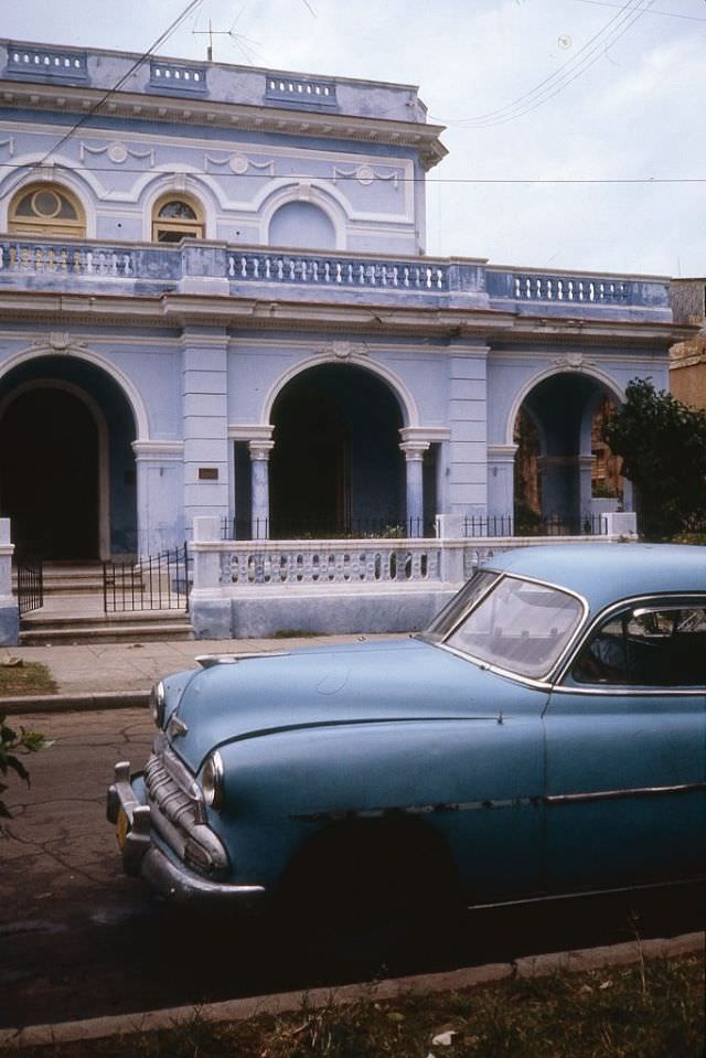 A dilapidated 1952 Chevrolet Deluxe parked outside a residential mansion in the Miramar neighborhood, Havana.