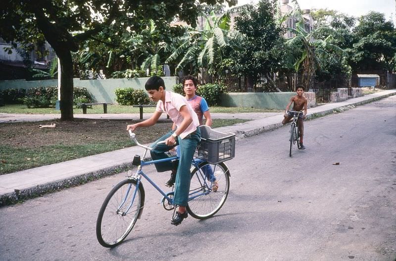 Three boys, two on bicycles, on a street in the Miramar neighborhood, Havana.