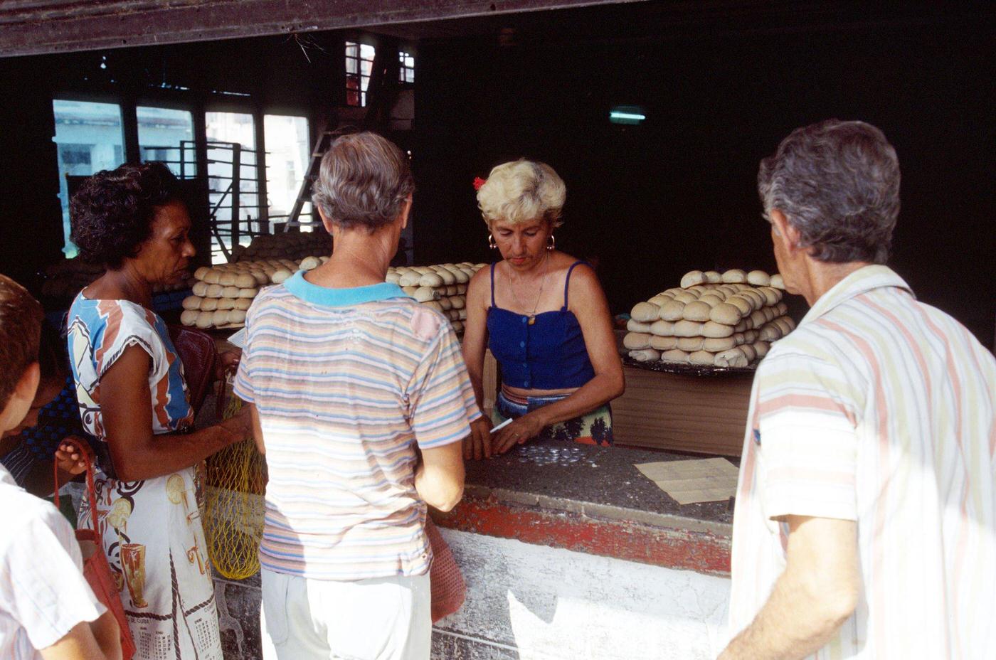 Cuban woman serving people at a public shop using the ration book in Havana, Cuba, 1990.