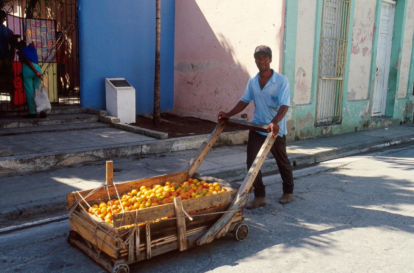 Cuban man carrying oranges on a cart, Cuba, 1990.