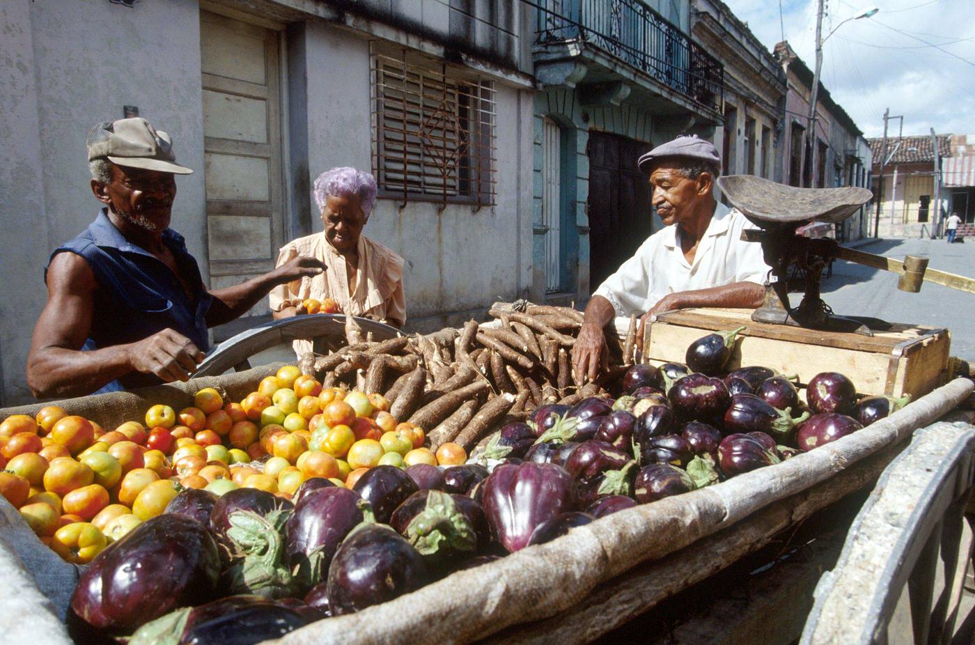 Cuban man selling fruits and vegetables displayed on a cart, Cuba, 1990.