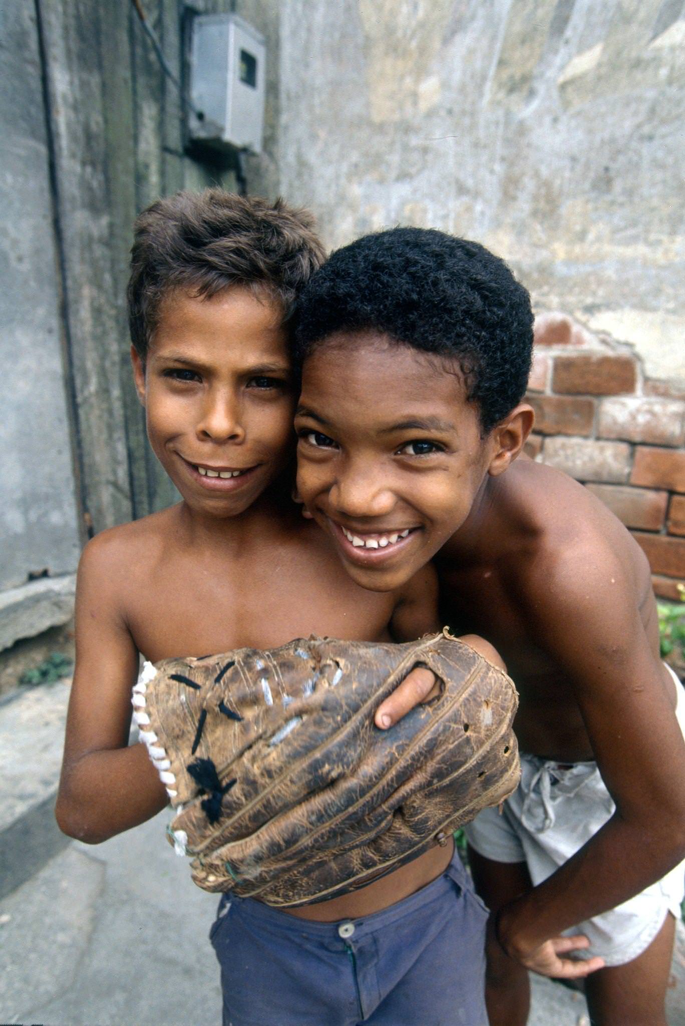 Two Cuban children posing while playing baseball in the street, Cuba, 1990.